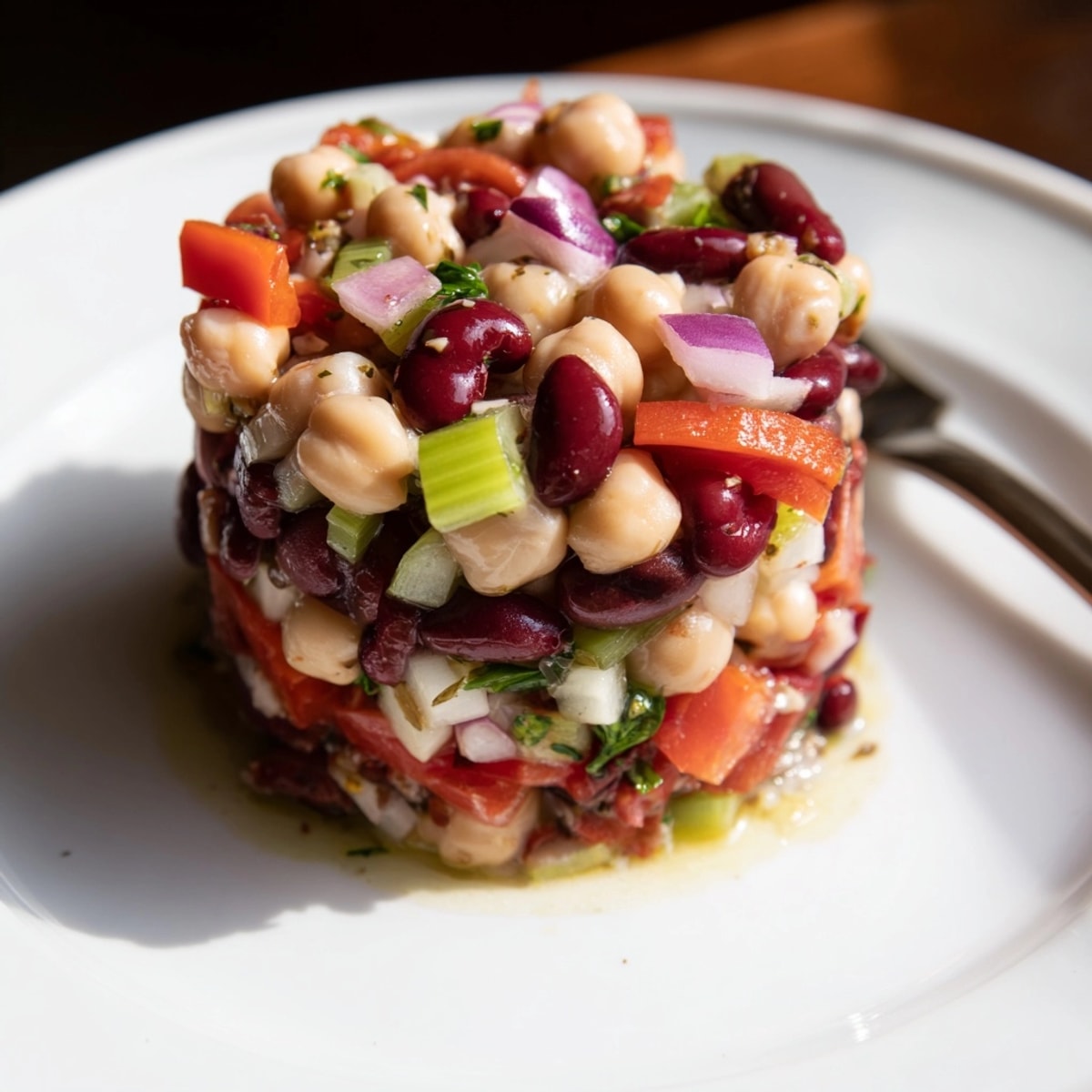 Close-up of a fresh Marinated Dense Bean Salad, showcasing layers of texture and bright veggies.