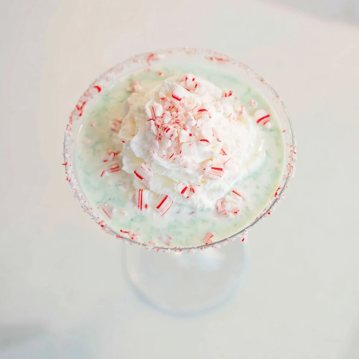 This Peppermint Twist cocktail is garnished with crushed candy canes, ready to sip.