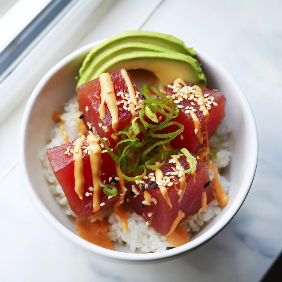 Overhead view of a fresh Spicy Tuna Poke Bowl with Sriracha Mayo and sesame seeds garnish.