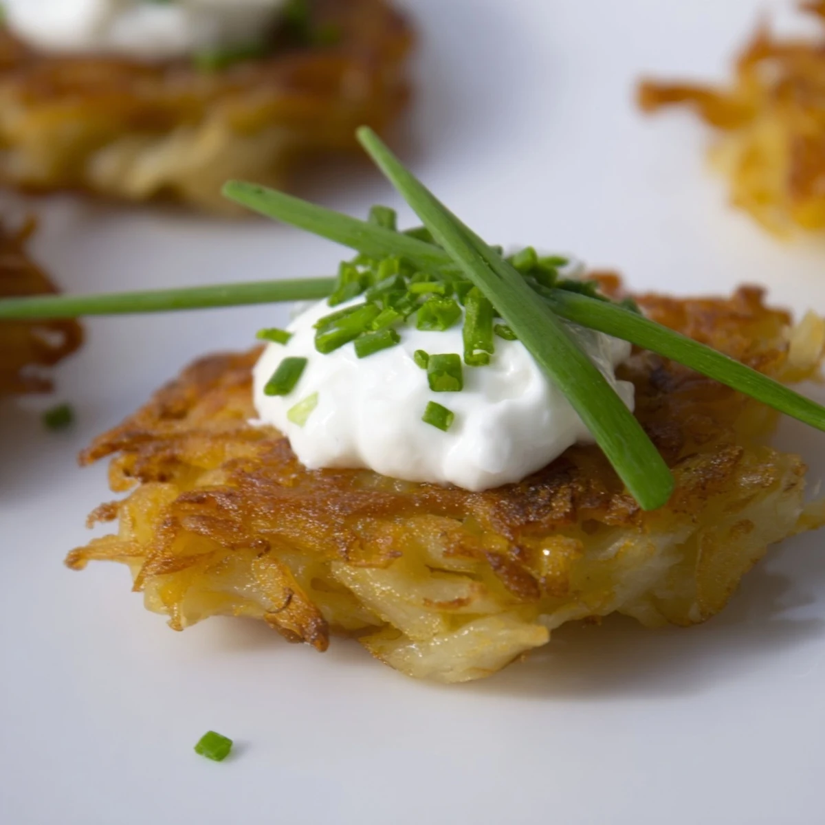 Golden, crispy Crispy Potato Latkes with cool sour cream and fresh chives, sizzling hot from the skillet. 