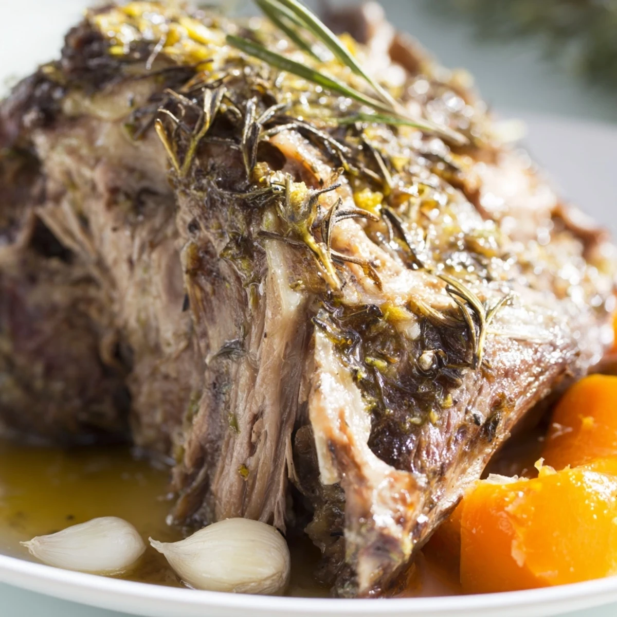 Succulent slow-roasted lamb shoulder with herbs, carved and ready to serve with rustic bread and fresh salad.