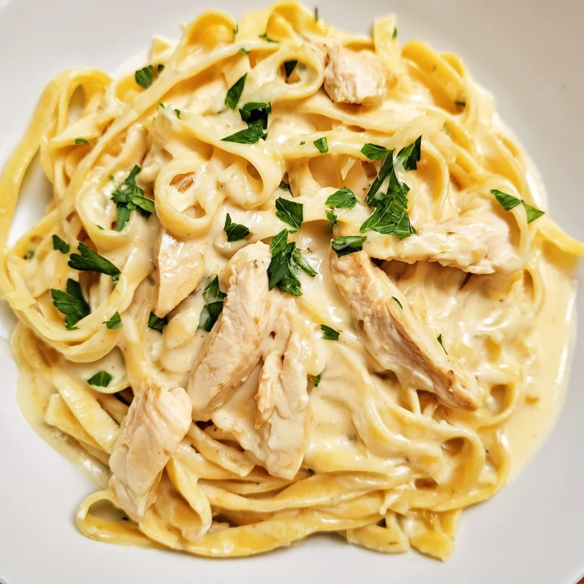 Creamy Chicken Alfredo pasta twirled on a fork with tender golden chicken in a velvety Parmesan sauce.