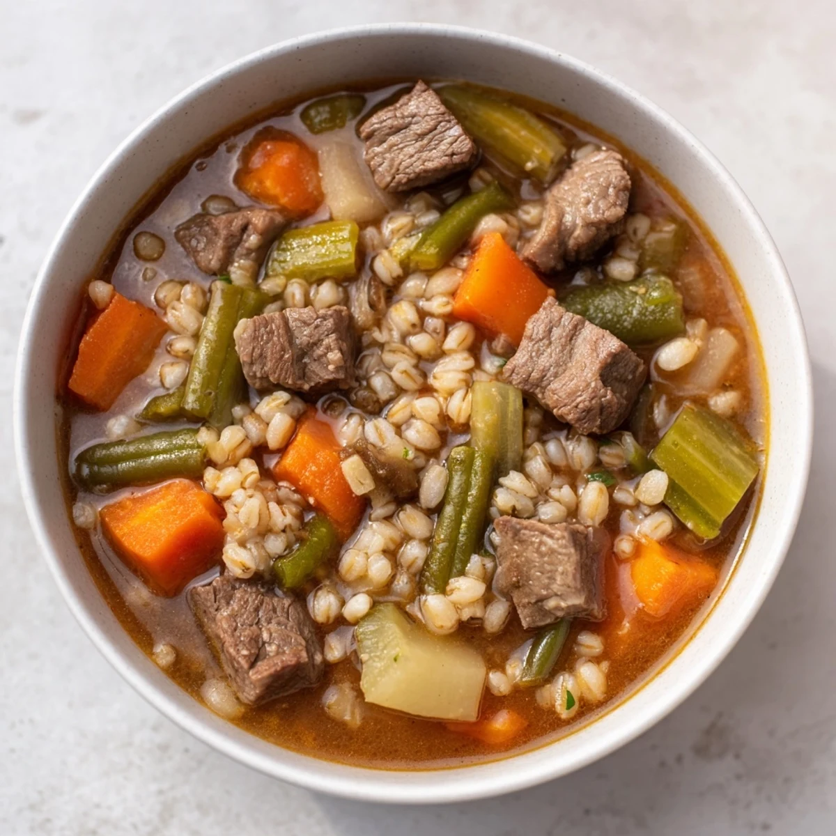 Close-up of Hearty Beef and Barley Vegetable Soup in a rustic bowl, highlighting the rich broth and vegetables.