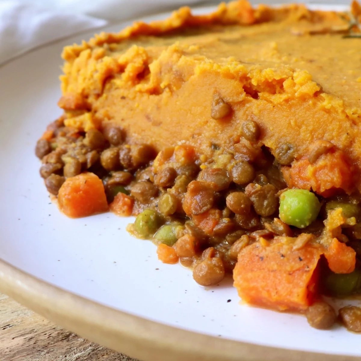 Close-up of Vegan Lentil and Sweet Potato Shepherds Pie topped with creamy orange mash and fresh thyme.