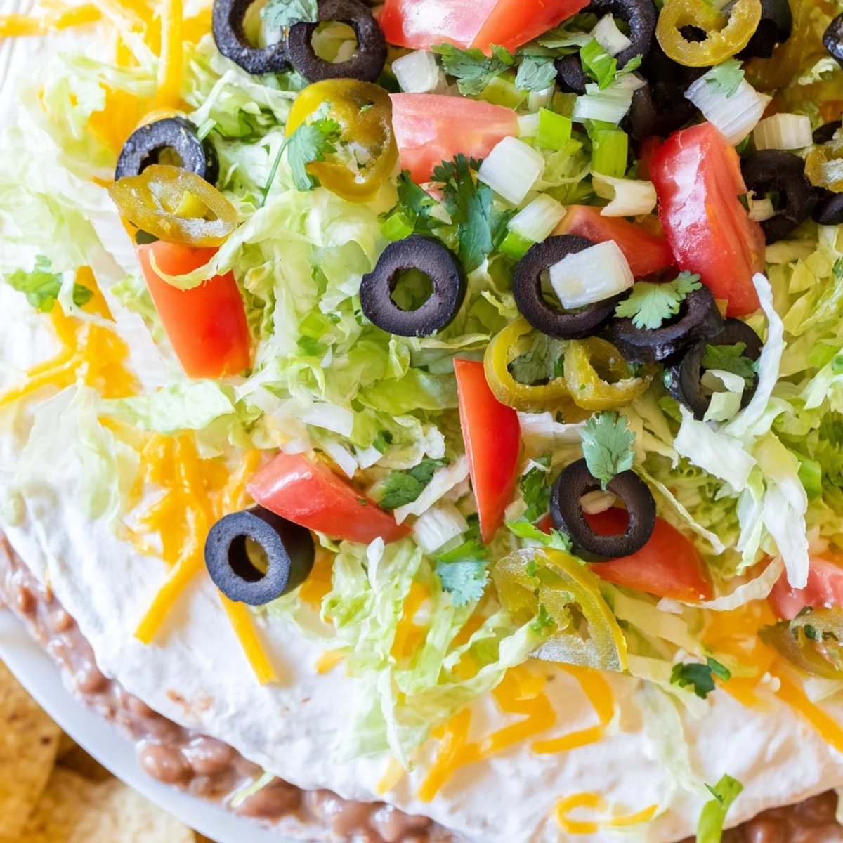 Serving suggestion of Ultimate Layered Taco Dip and tortilla chips for game day gatherings.