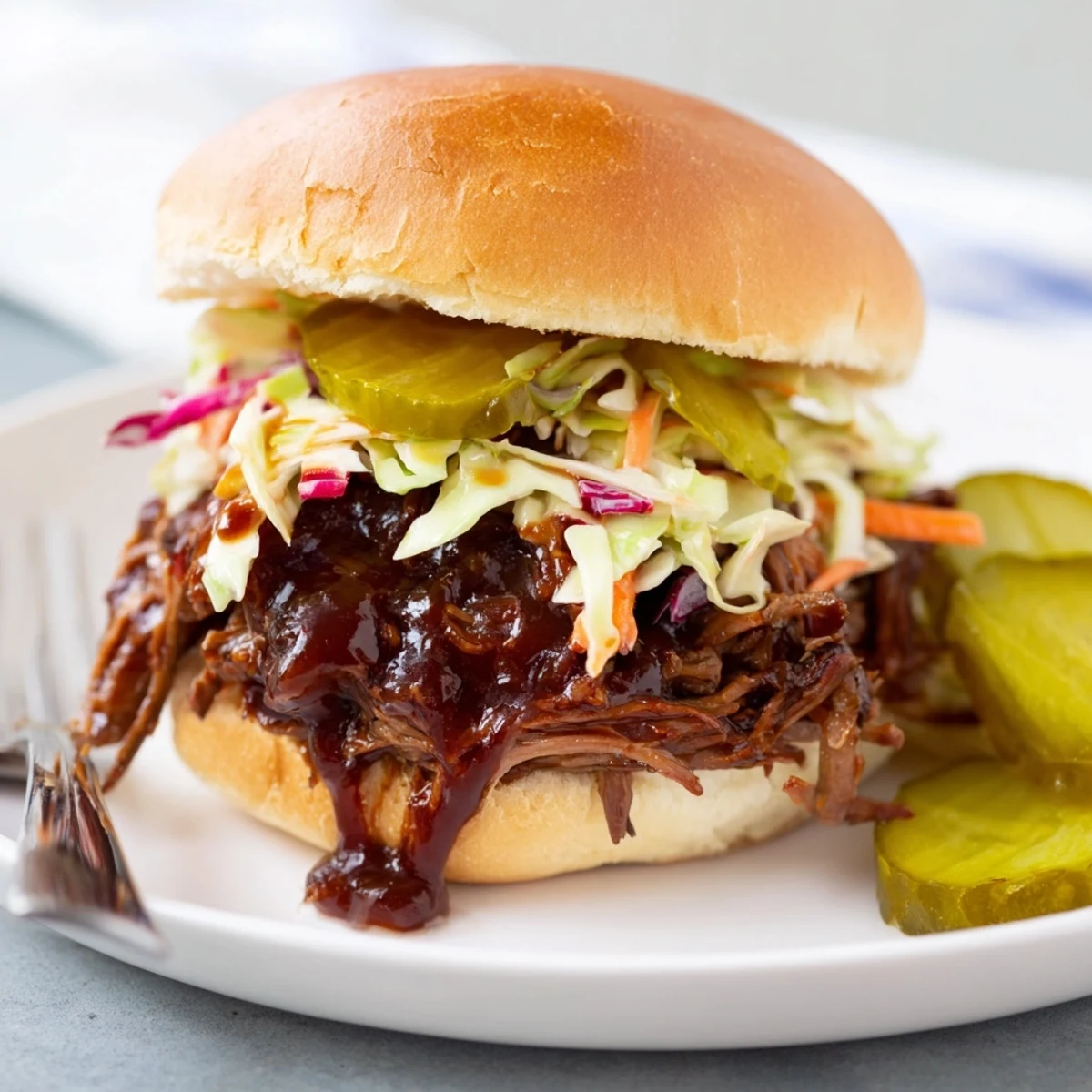Smoky shredded beef brisket piled on soft slider buns with creamy coleslaw and crunchy dill pickles for a perfect party bite.  