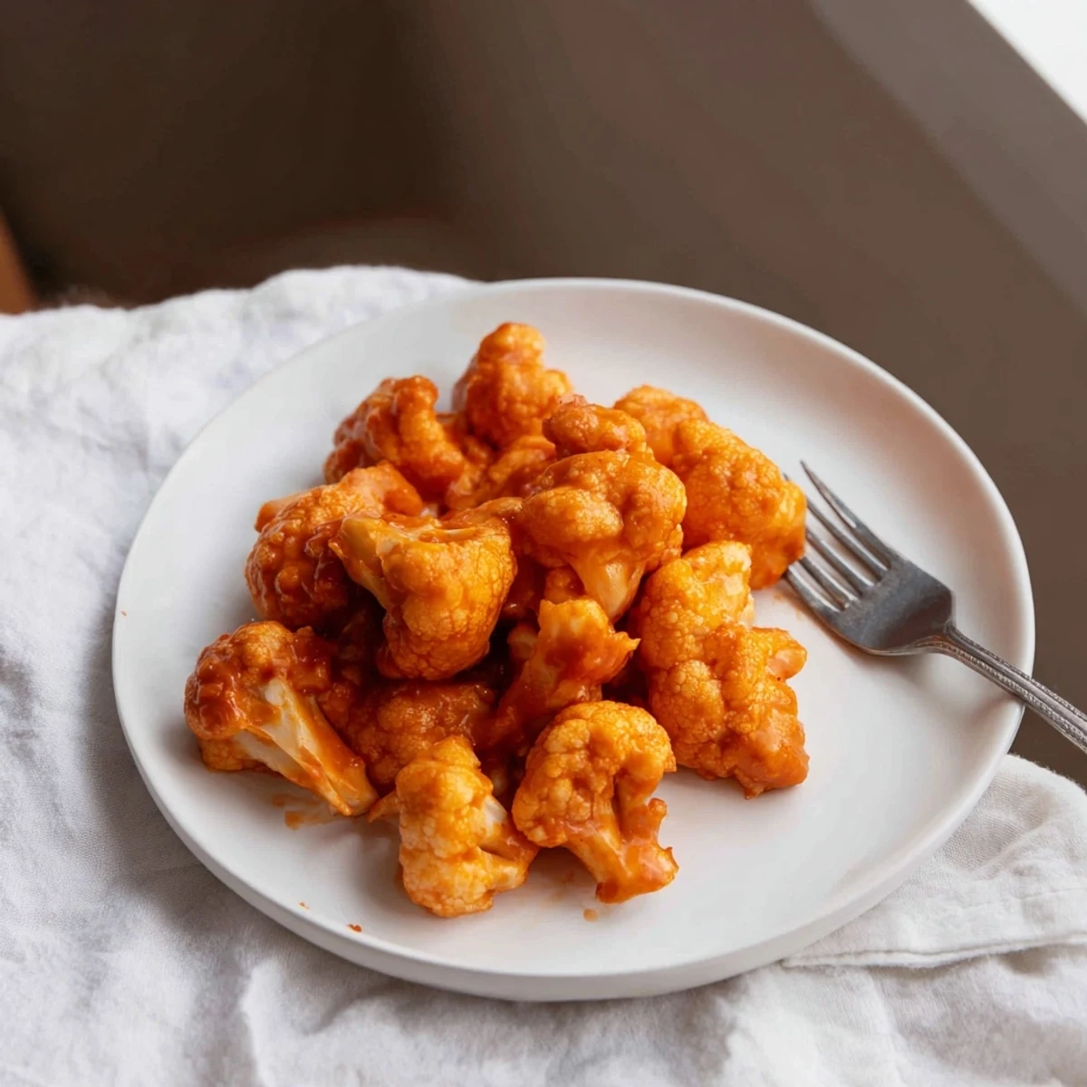 Perfectly baked cauliflower florets tossed in spicy buffalo sauce, arranged with celery and carrot sticks for a classic appetizer platter.