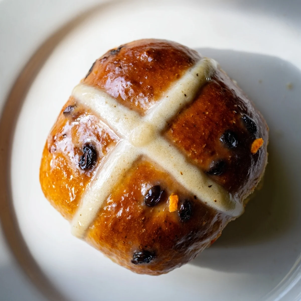 Close-up of a soft hot cross bun with a classic cross on top, revealing a tender, currant-filled interior perfect for toasting.