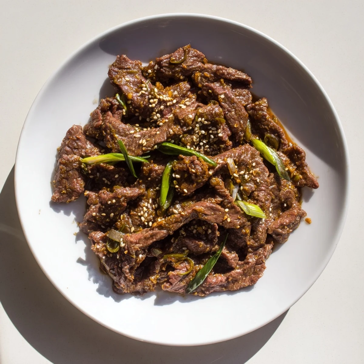 Sliced flank steak coated in cornstarch cooks in a glossy, savory-sweet sauce inside the slow cooker for Ultimate Slow Cooker Mongolian Beef