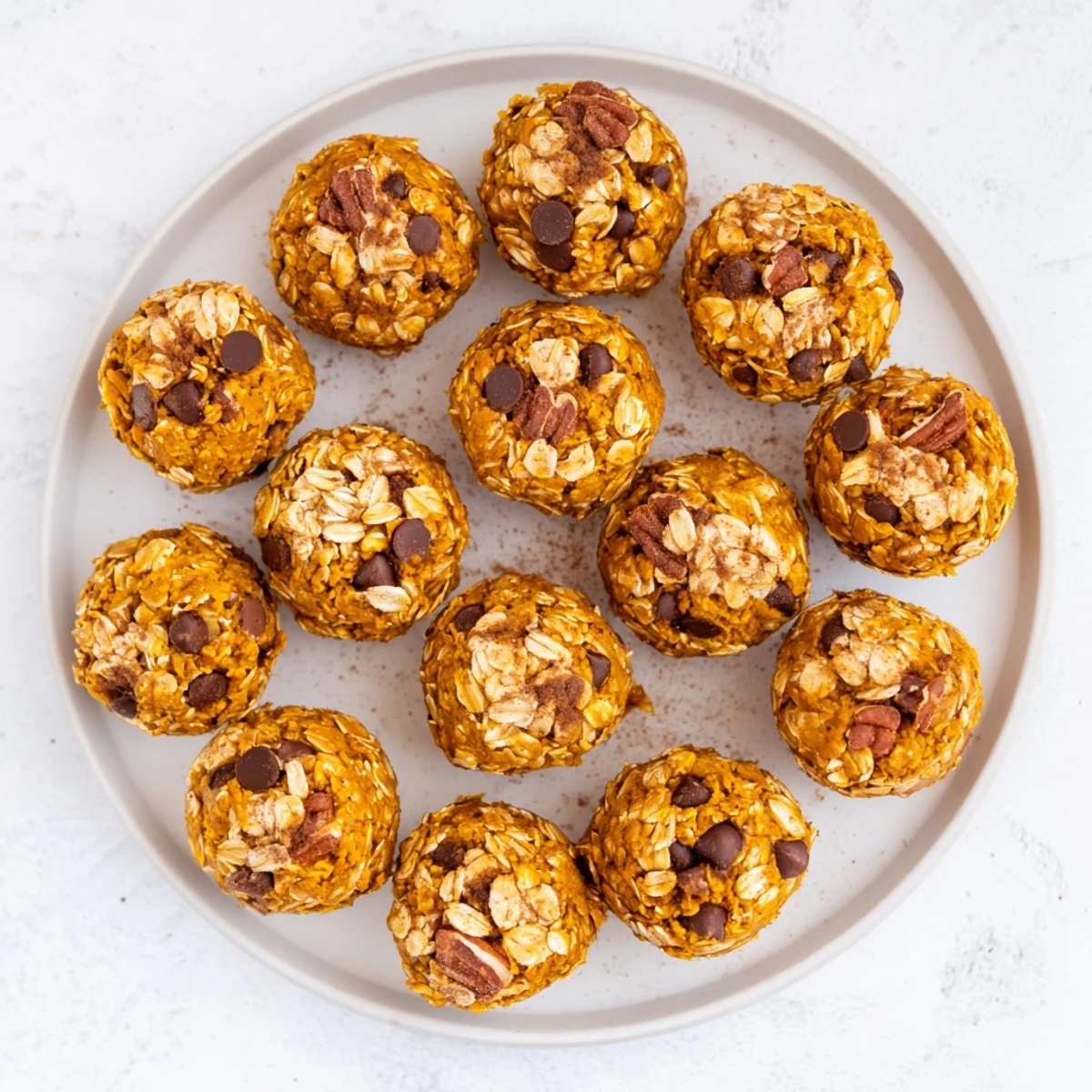 These No Bake High Protein Pumpkin Bites on a wooden board are dusted with cinnamon and filled with oats and nuts.