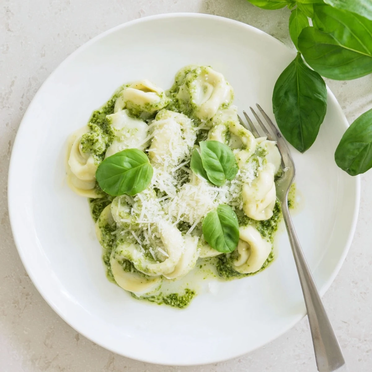 A rustic wooden table holds a skillet of steaming Pesto Alfredo Tortellini next to a glass of white wine.