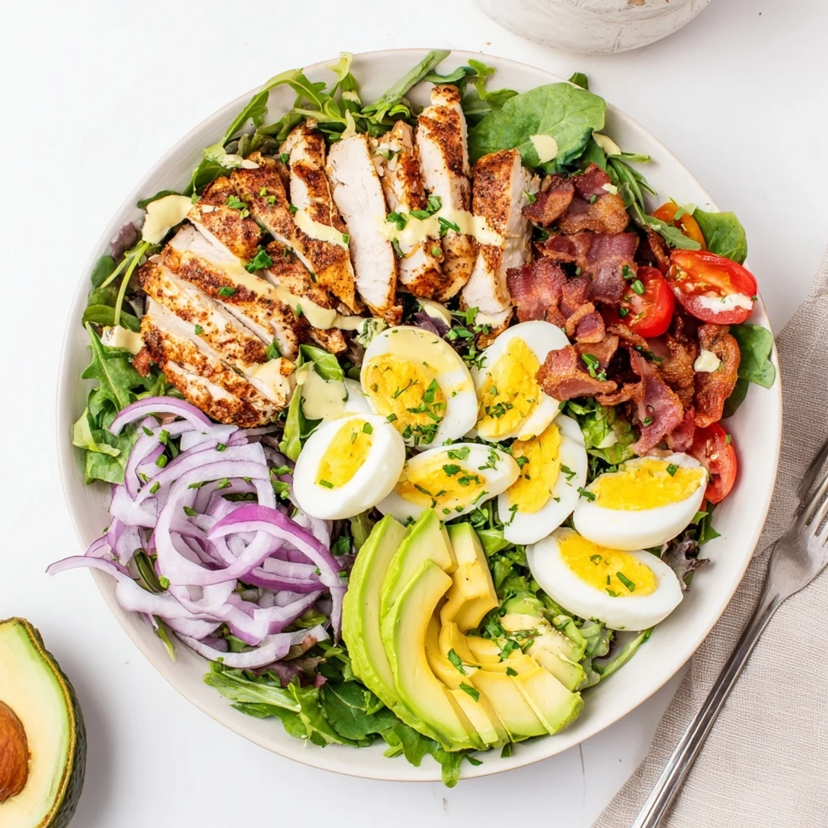 Grilled chicken slices, crispy bacon, and creamy avocado atop fresh greens for the Paleo Grilled Chicken Cobb Salad With Honey Dijon Dressing.