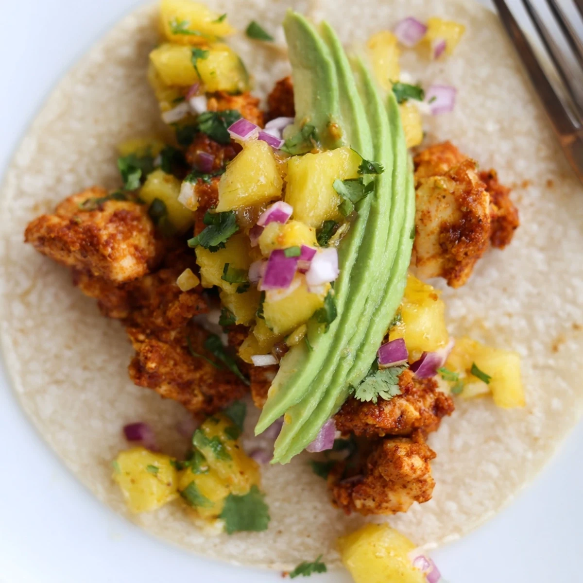 Close-up of juicy grilled chicken and fresh pineapple salsa stuffed into warm corn tortillas for Pineapple Chicken Tacos, served with avocado slices.