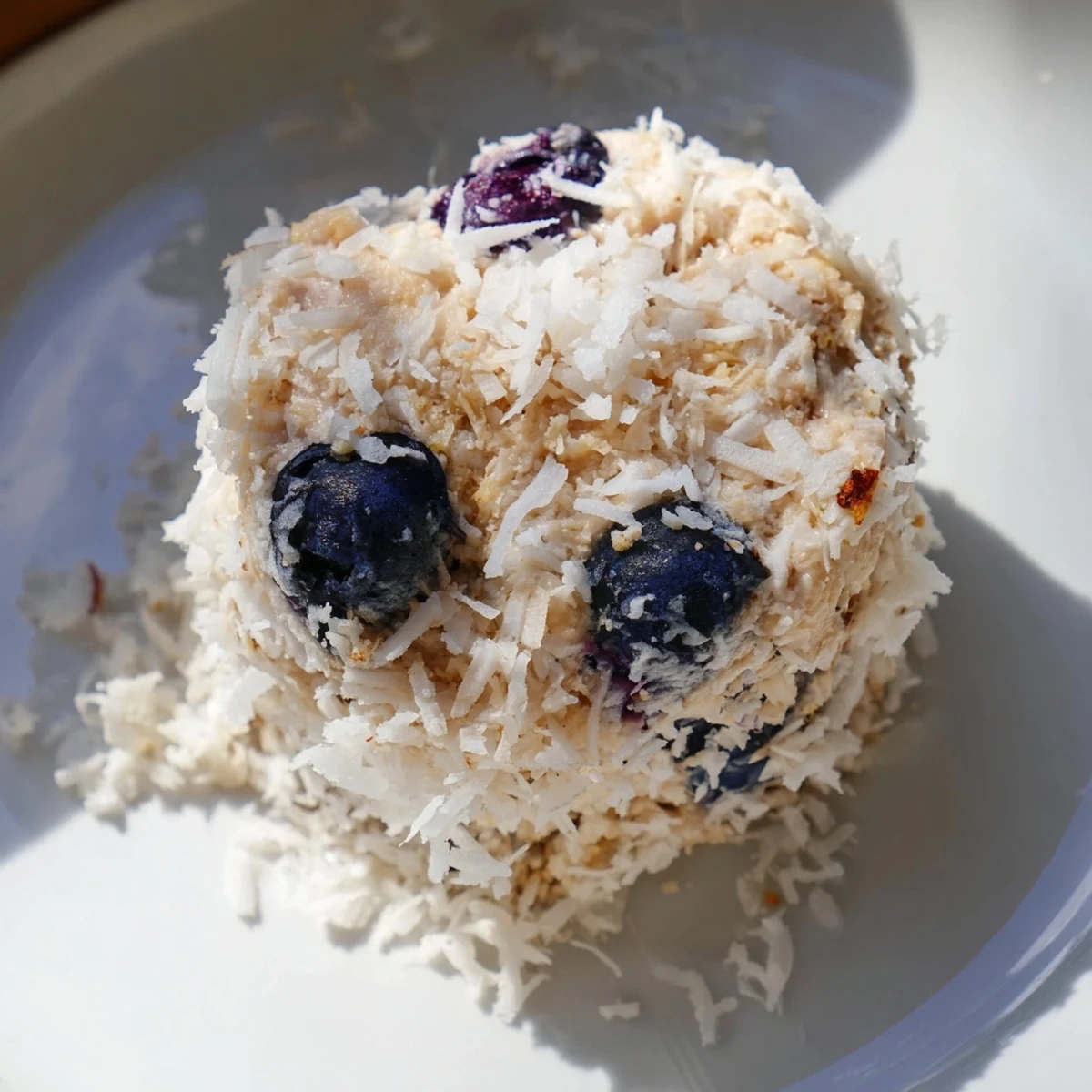 Bright Lemon Blueberry Cottage Cheese Protein Bites stacked on a white plate.