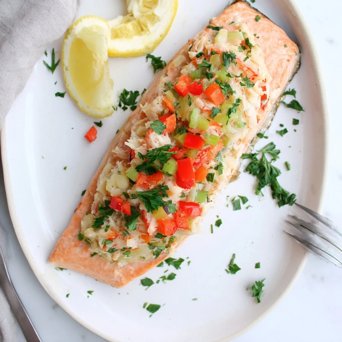 Flaky baked Crab & Shrimp Stuffed Salmon served with lemon wedges on a plate.