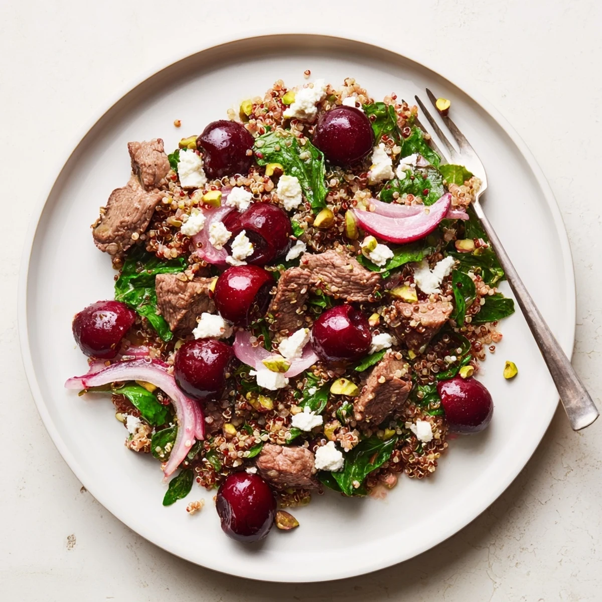 Mediterranean-style cherry quinoa salad featuring tender lamb, feta cheese, and mint in a shallow bowl