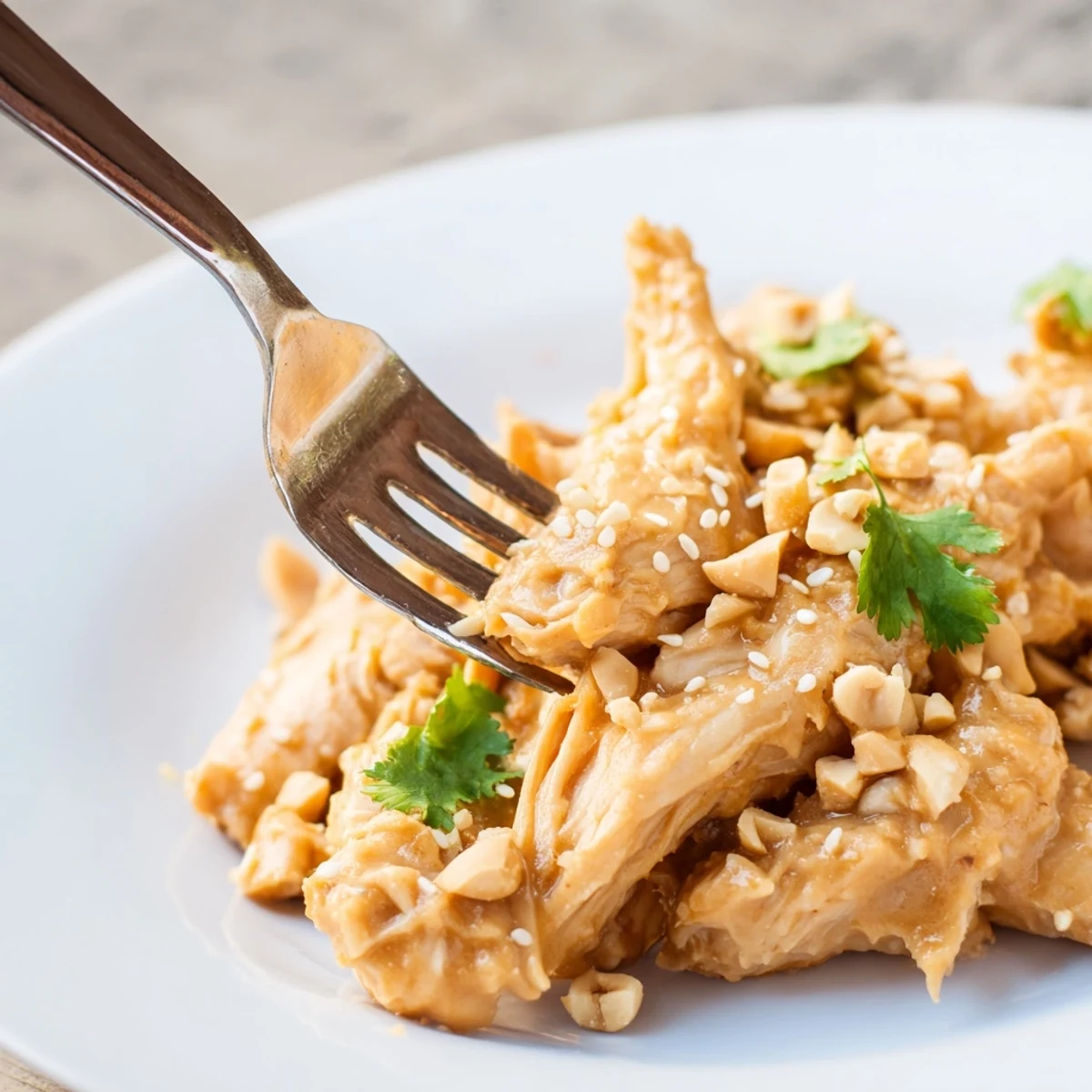 Crockpot peanut chicken with succulent thighs coated in glossy peanut butter sauce alongside diced onions peppers and fragrant steamed rice