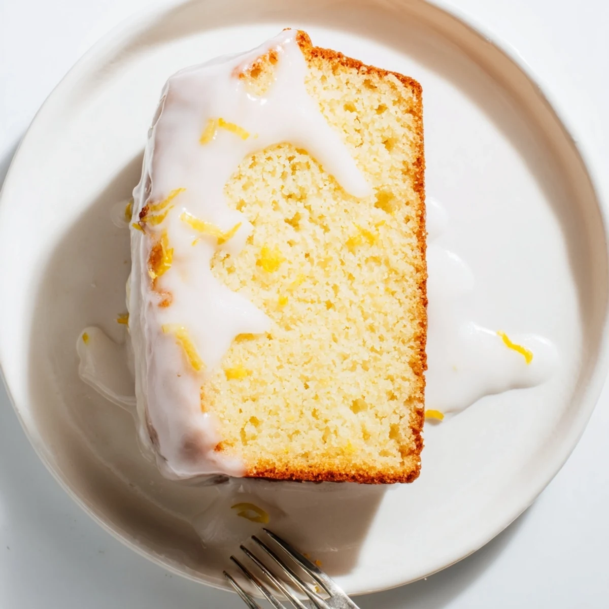 Moist lemon loaf cake with zesty glaze served alongside a steaming cup of Earl Grey tea