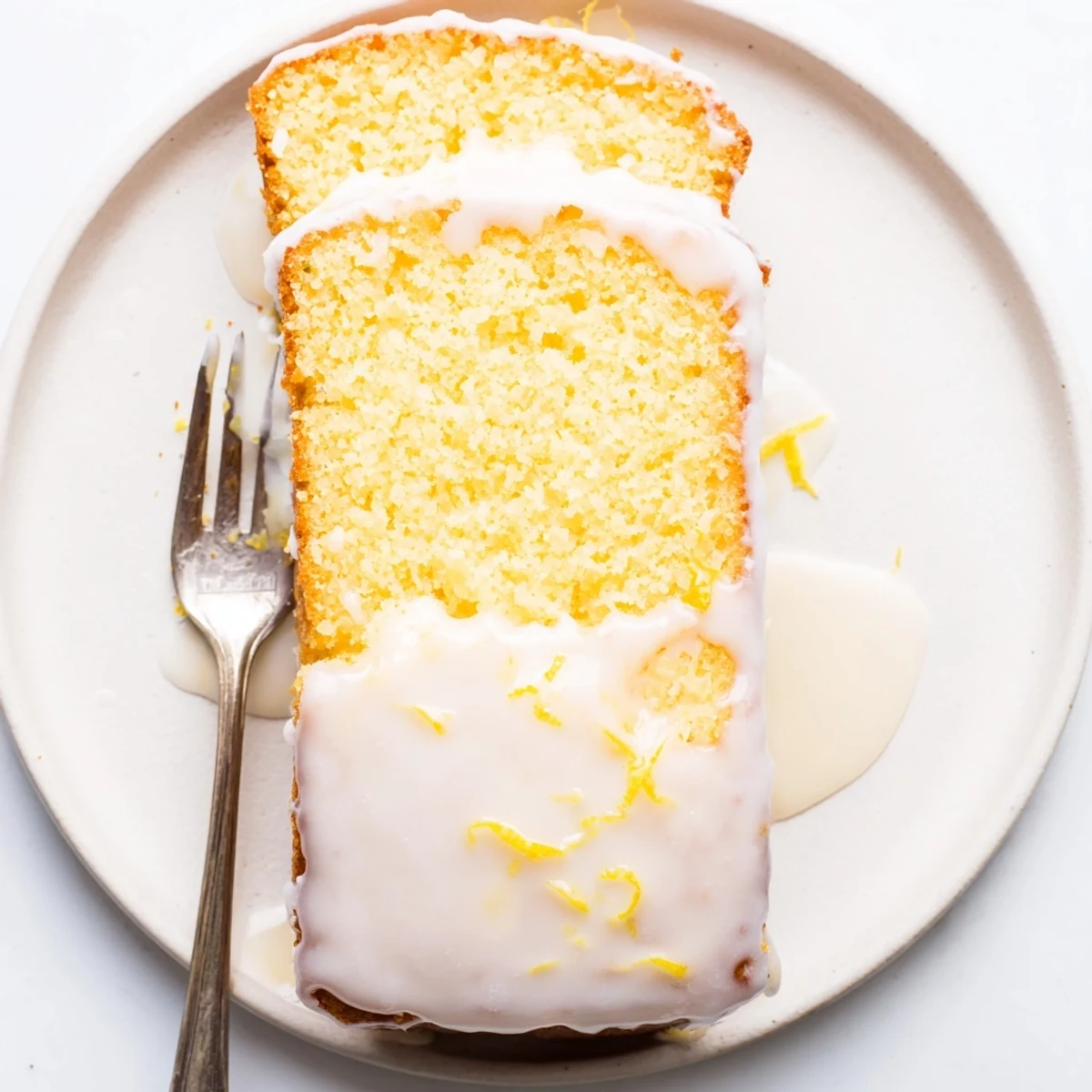 Freshly baked lemon loaf topped with creamy white icing and garnished with lemon zest curls