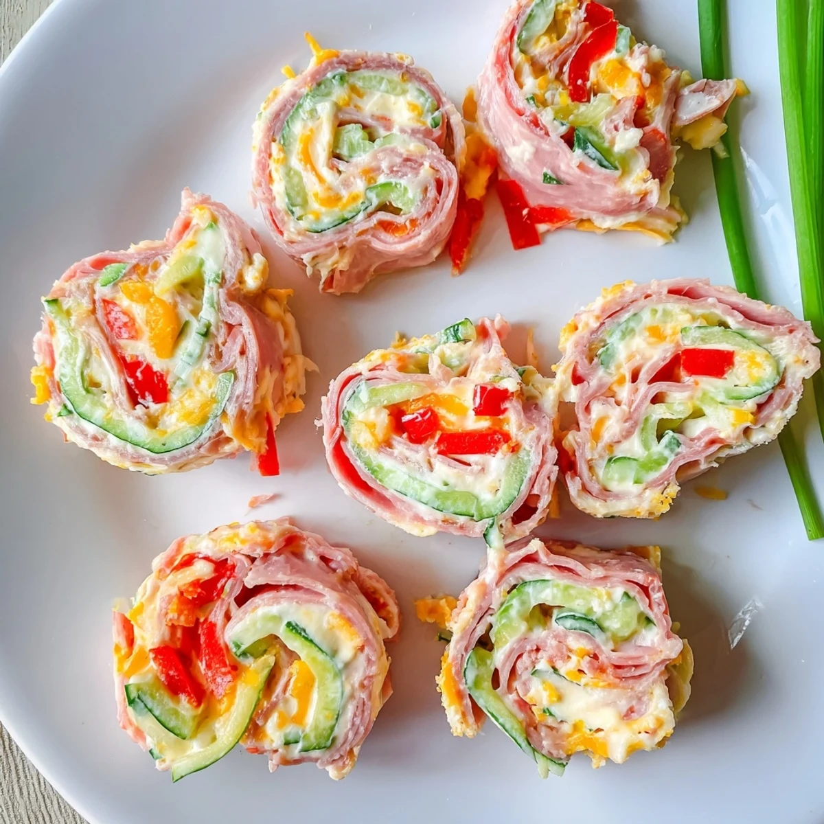 Close-up view of savory keto ham roll ups displaying the layered cream cheese spread and julienned vegetables tucked inside thin ham slices
