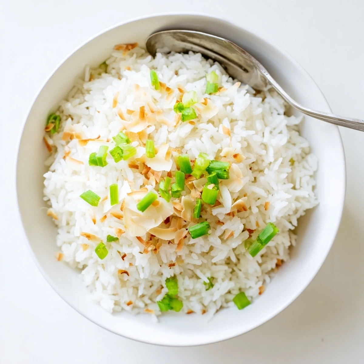 Fluffy coconut rice garnished with toasted coconut flakes and fresh cilantro in a serving bowl