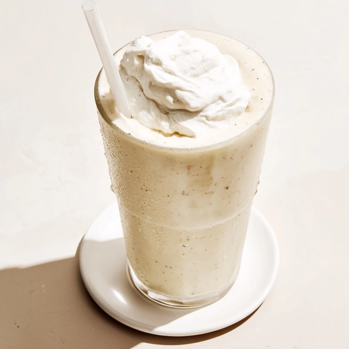 Smooth blended vanilla frappuccino with visible vanilla bean specks and ice crystals