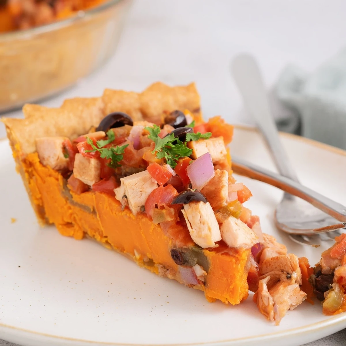 Golden sweet potato chicken pie topped with vibrant tomato olive salsa on a white plate