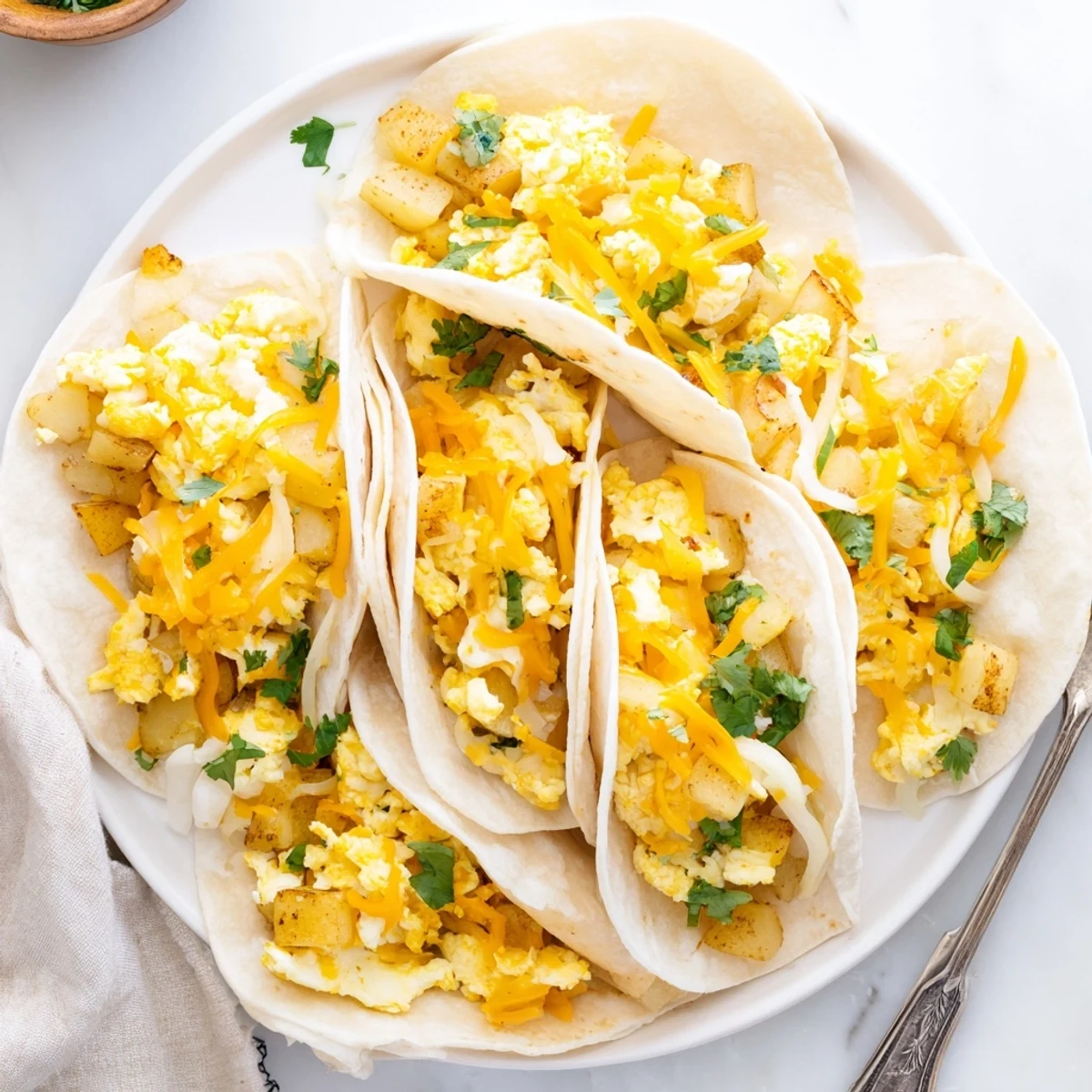 Golden potato egg cheese breakfast tacos piled high on a wooden serving board