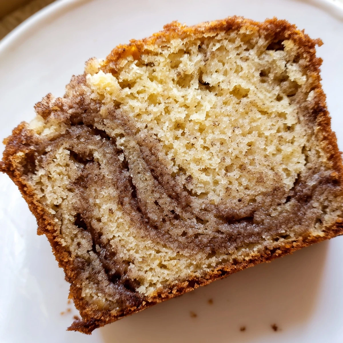Moist cinnamon sugar swirl banana bread with golden crust displayed on rustic wooden cutting board